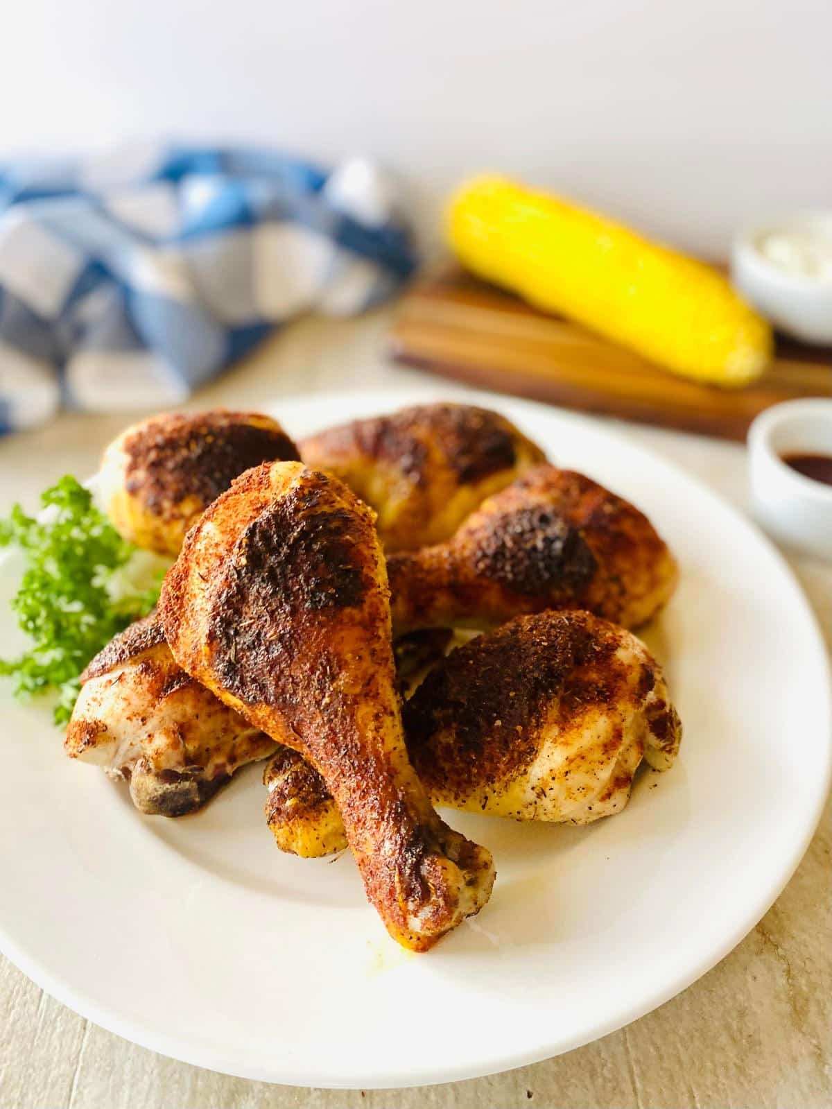 traeger Chicken Legs cooked on pellet grill on plate with corn.
