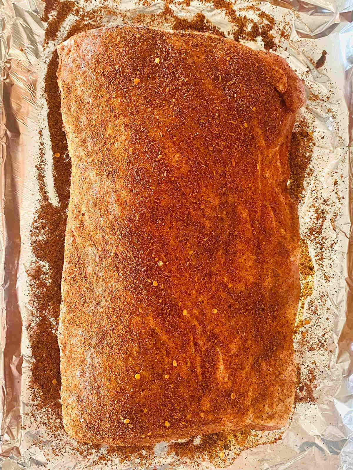 pork loin covered in olive oil and seasoning dry rub.