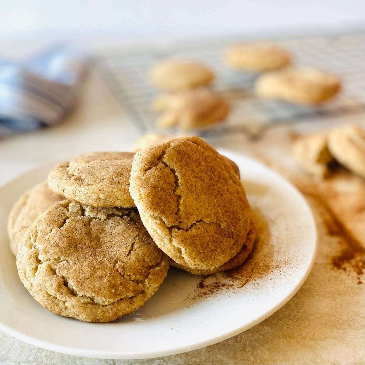 easy snickerdoodle recipe without cream of tartar on white plate with tray of snickerdoodle cookies in background