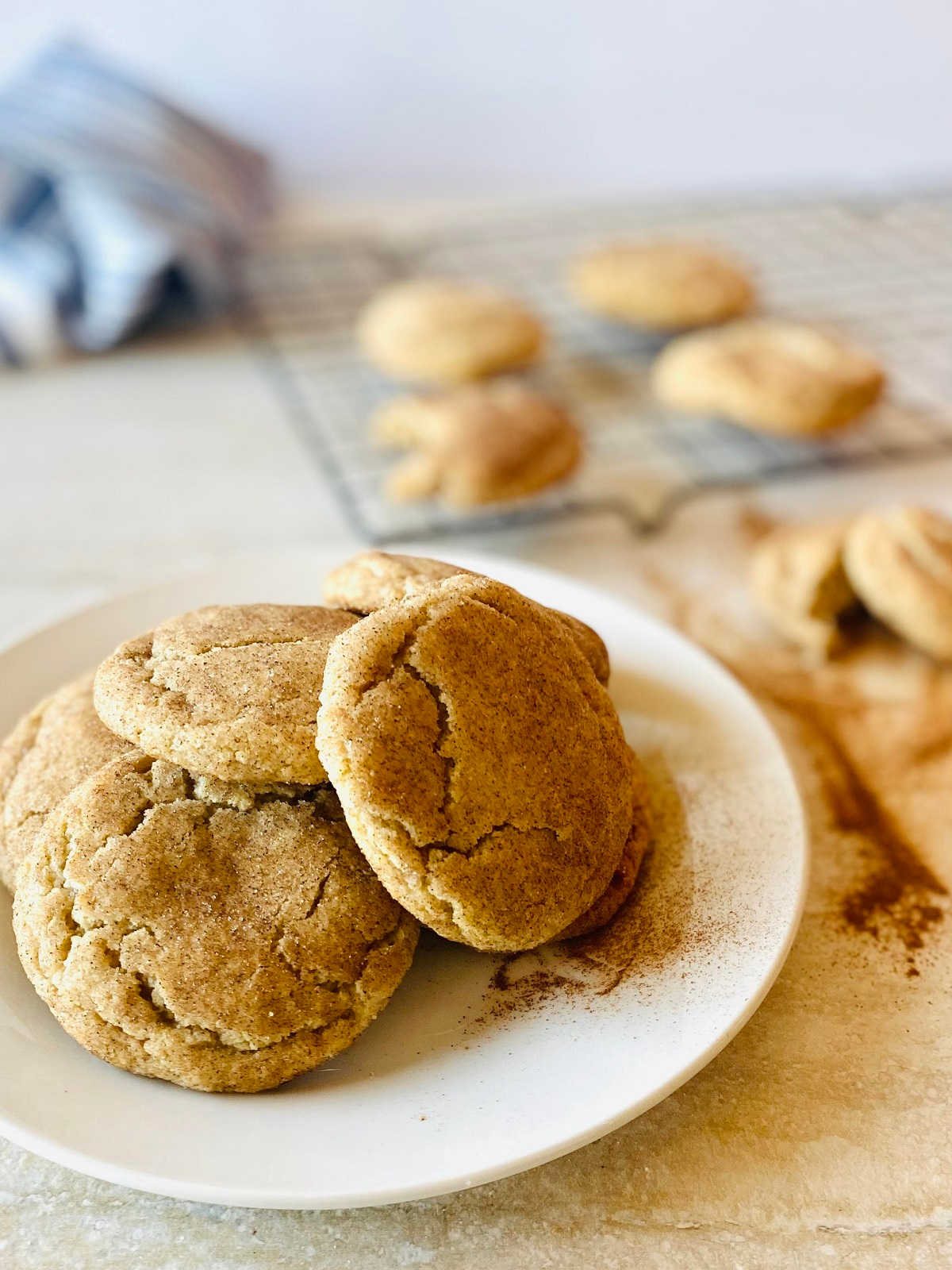 snickerdoodle recipe without cream of tartar on white plate with tray of snickerdoodle cookies in background