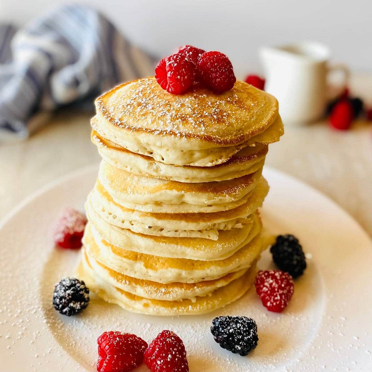 almond milk pancakes in a stack on a plate topped with raspberries