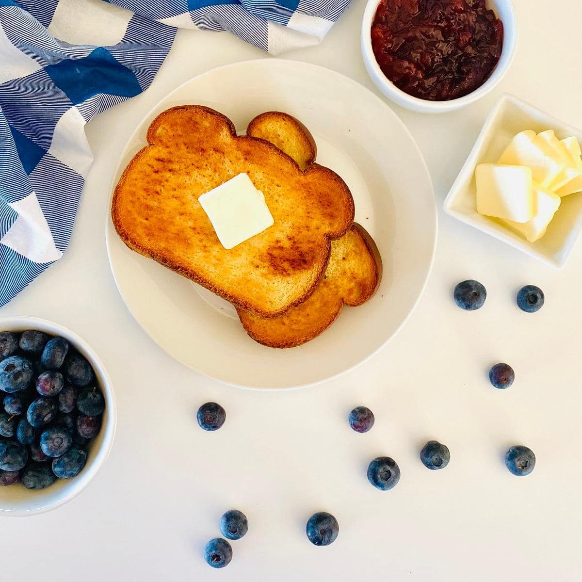 air fryer toast on plate with a slice of butter, next to jam and butter
