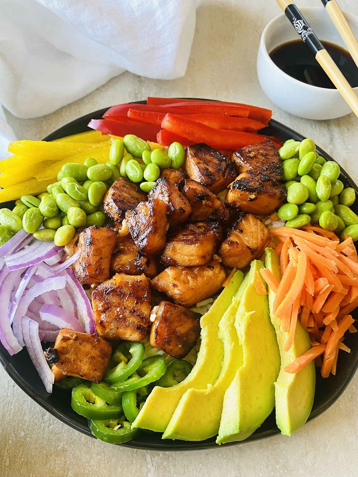 spicy salmon bowl next to soy sauce