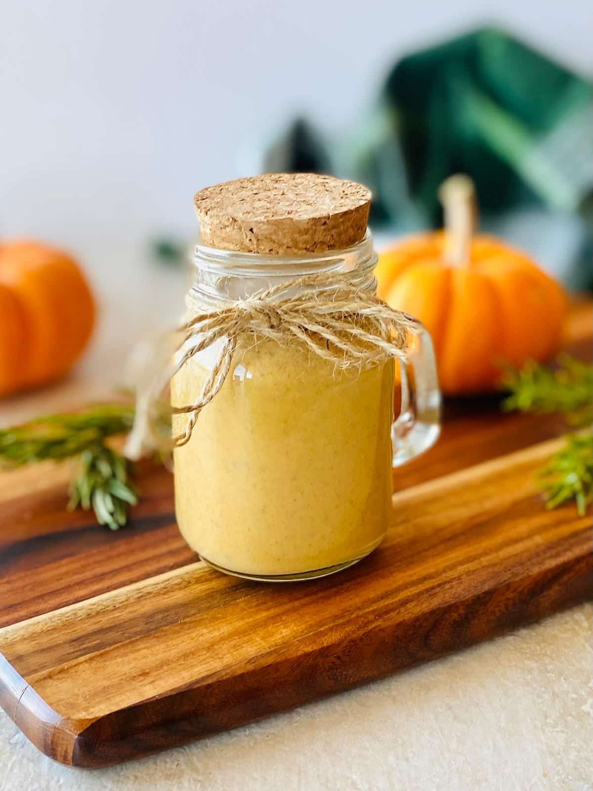 starbucks pumpkin spice syrup in a jar with a pumpkin in the background.