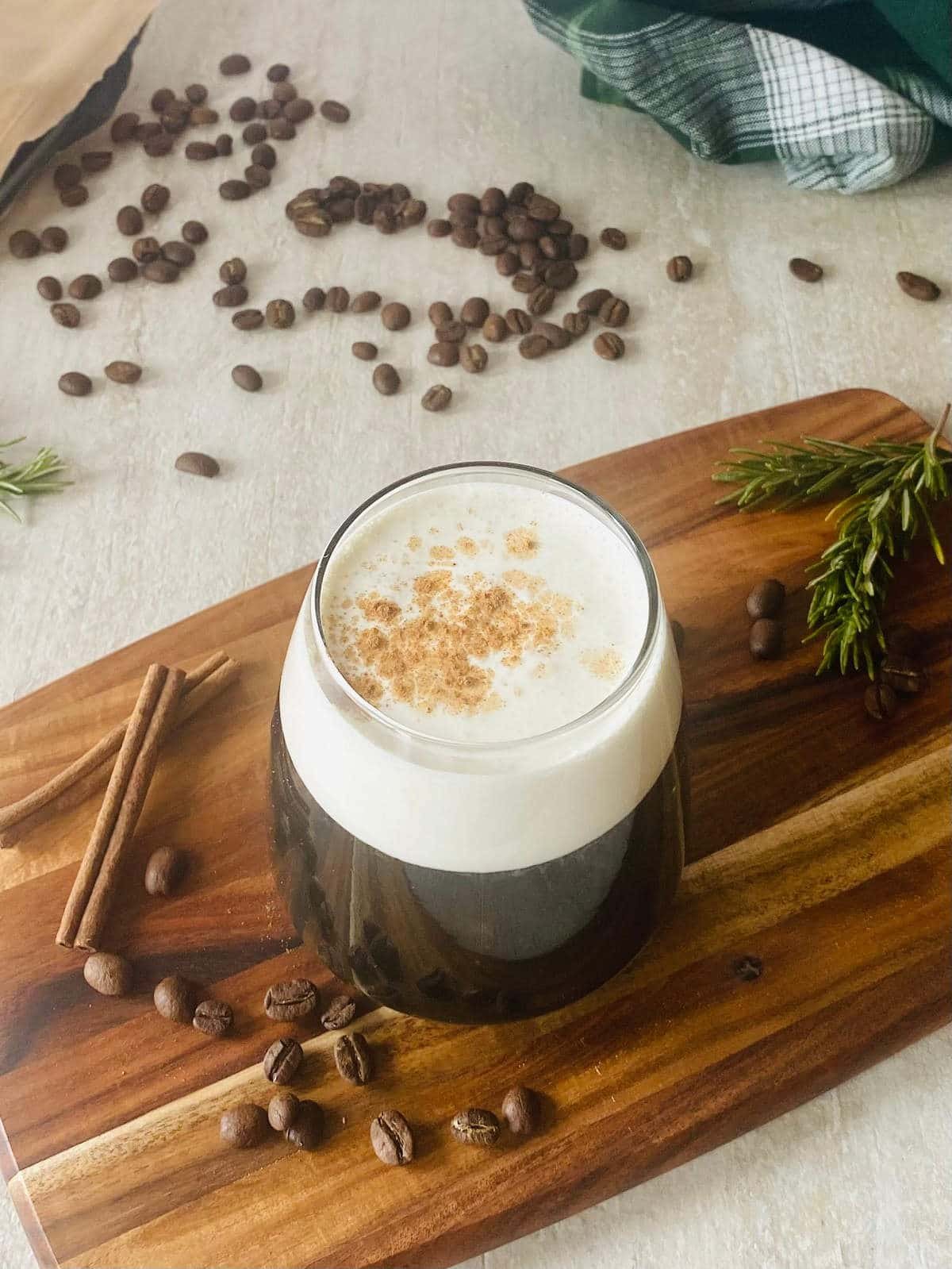 starbucks sweet cream cold brew coffee next to coffee beans and cinnamon sticks.