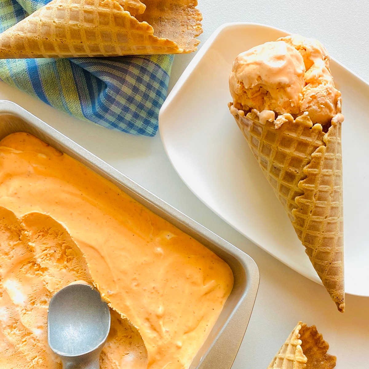 thai tea ice cream in metal tin next to ice cream cones
