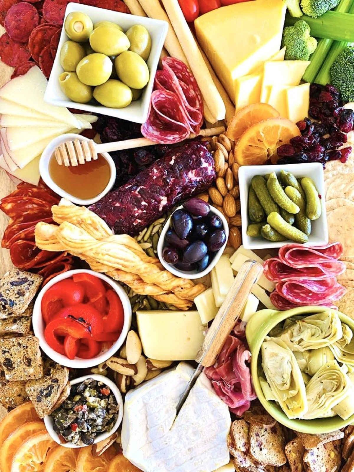 trader joe's charcuterie board with honey pickles red peppers vegetables nuts fruits cheese meat and dips and spreads