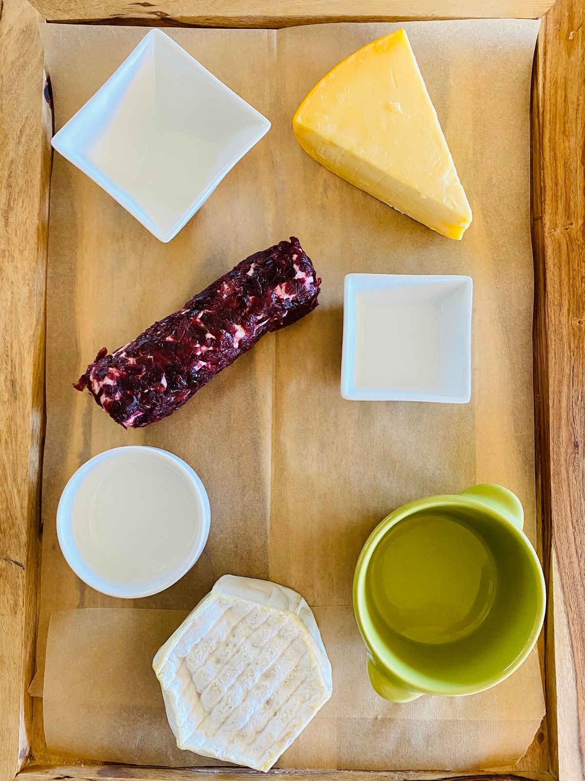 charcuterie board with bowls and two cheeses assembled