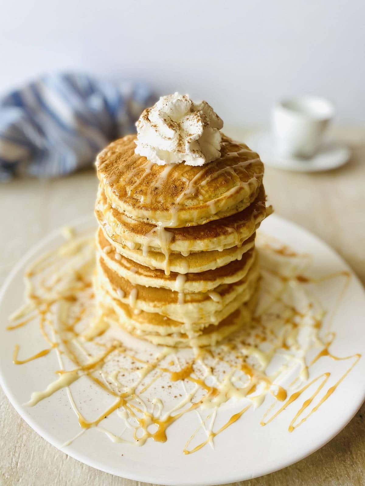 copycat ihop tres leches pancakes on a plate drizzled with tres leches syrup, caramel dulce de leche and whipped cream