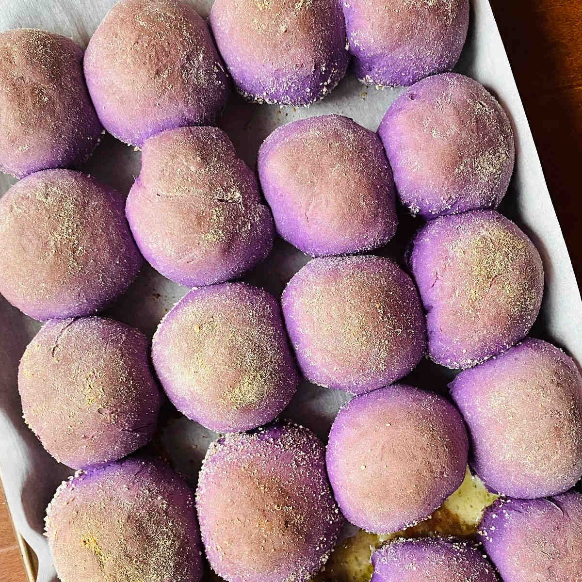 freshly baked ube pandesal rolls on baking sheet
