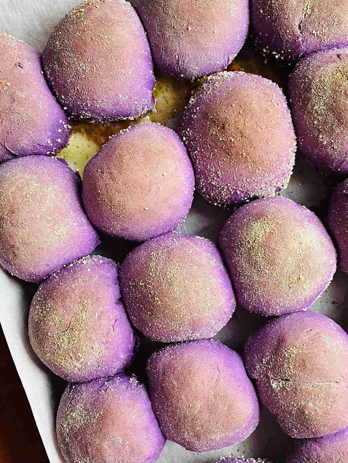 freshly baked ube pandesal with cheese on baking sheet
