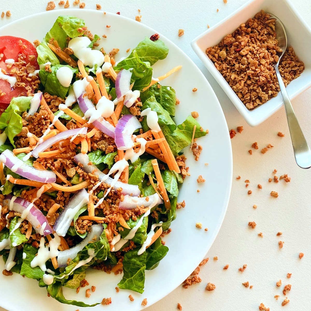 vegan bacon bits in white dish next to salad with ranch dressing and bacon bits
