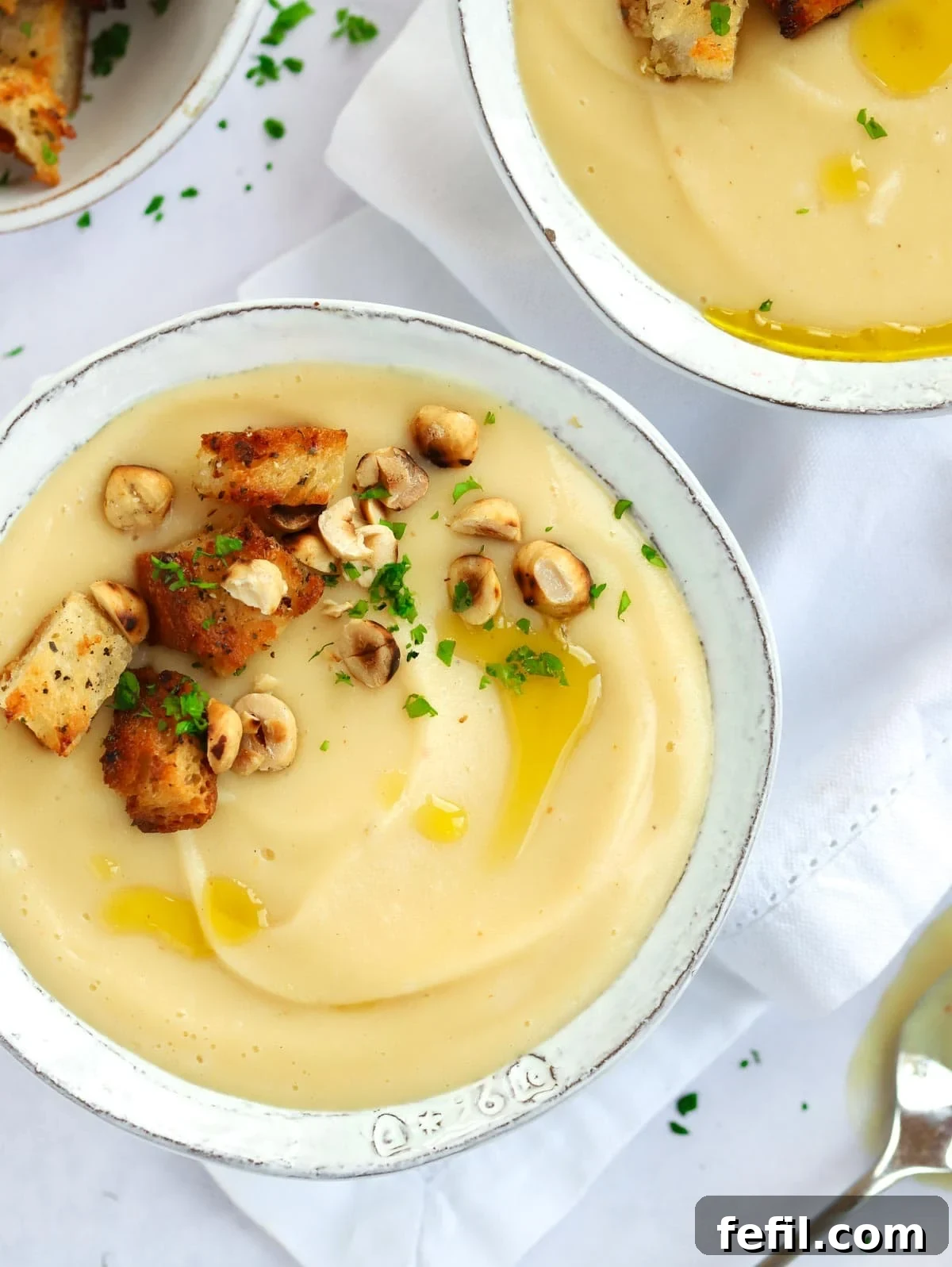 Simple 20 Minute Parsnip Soup 4 A bowl of parsnip soup on a white tablecloth with croutons.
