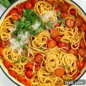 A big pan filled with cooked spaghetti and tomatoes, topped with parmesan and basil, for the recipe Tomato Pasta.