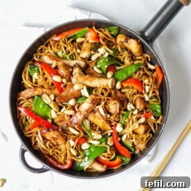 Overhead photo of pork stir fry recipe with noodles, pork, red peppers and mange tout and peanuts.