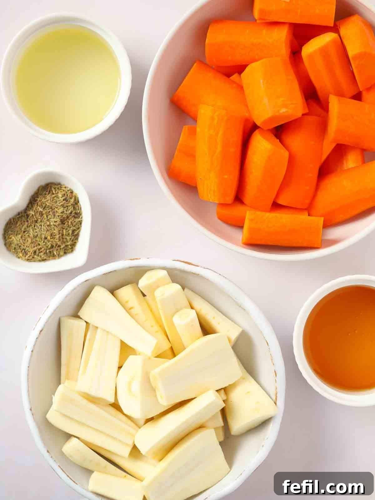 Sweet Honey-Kissed Roasted Roots 4 Raw parsnips, carrots, a bottle of sunflower oil, honey, and a sprig of thyme arranged on a white kitchen counter, showcasing fresh ingredients.