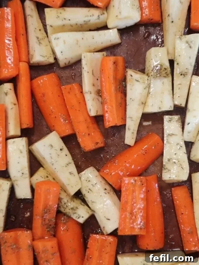 Sweet Honey-Kissed Roasted Roots 6 Step-by-step image showing the coated carrots and parsnips spread in a single layer on a lined baking sheet, ready for the oven.