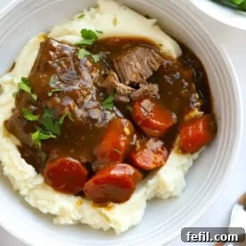 Delicious braised steak with tender carrots in rich gravy served over a bed of creamy mashed potato.