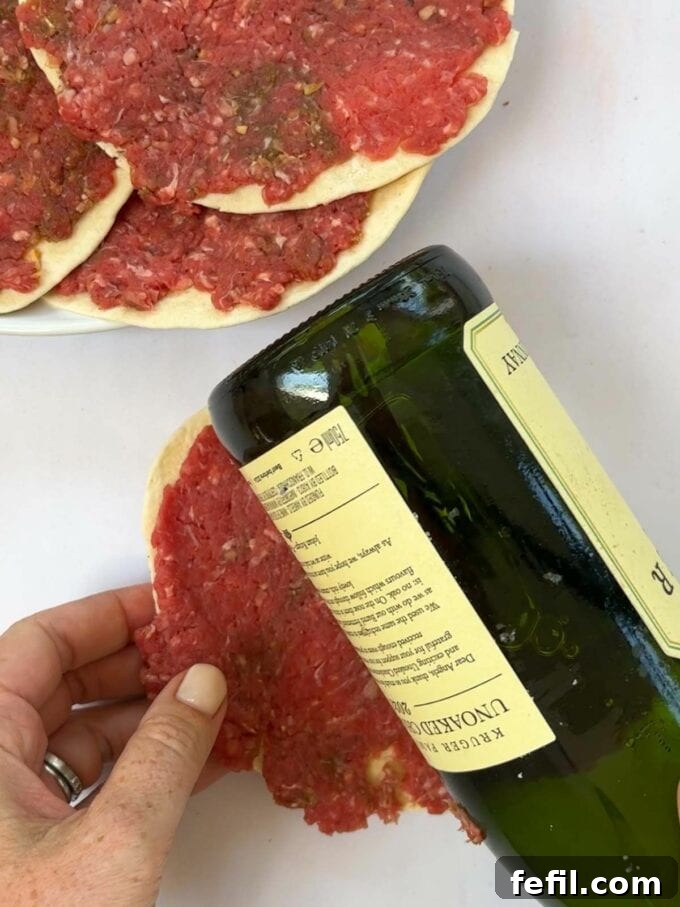 Big Mac Taco Mashup 7 Rolling beef patties onto a tortilla wrap with a wine bottle to flatten it, demonstrating a practical kitchen hack.