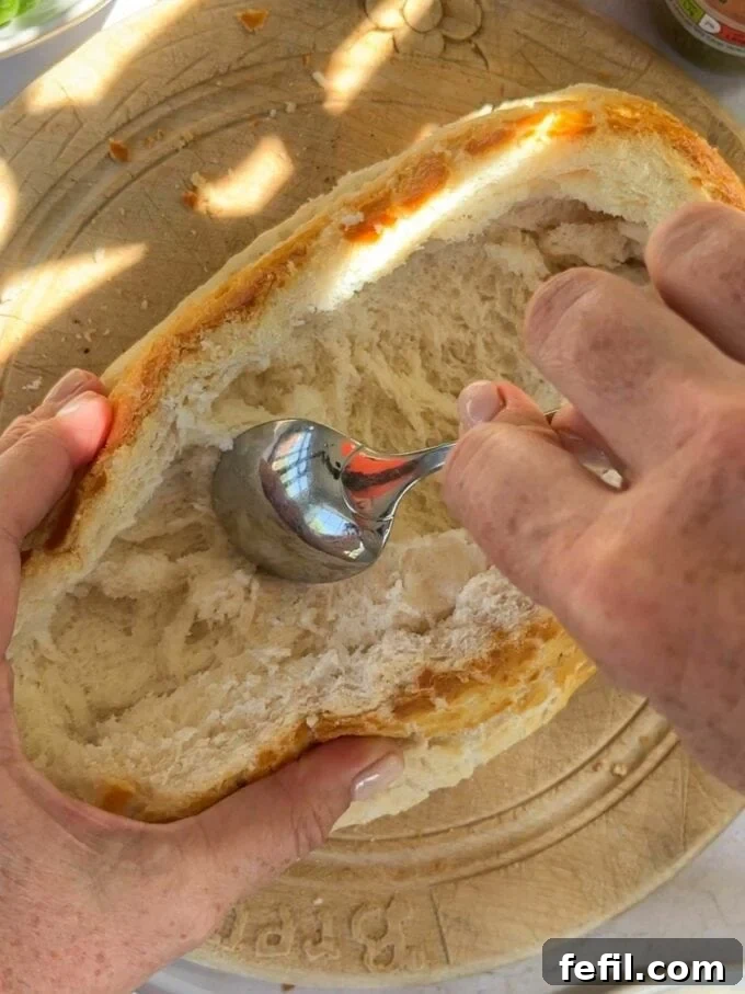 Step 1 in the method of how to make a stuff picnic loaf. Hollow out a loaf of fresh bread and remove the inside.