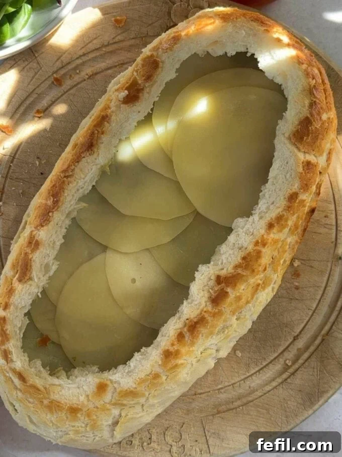 The next step to make a stuff picnic loaf is to add a layer of cheese.
