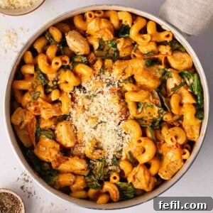 A bird's eye view of creamy Marry Me Chicken Pasta in a pan, garnished with fresh spinach, grated Parmesan cheese, and ready to be served.