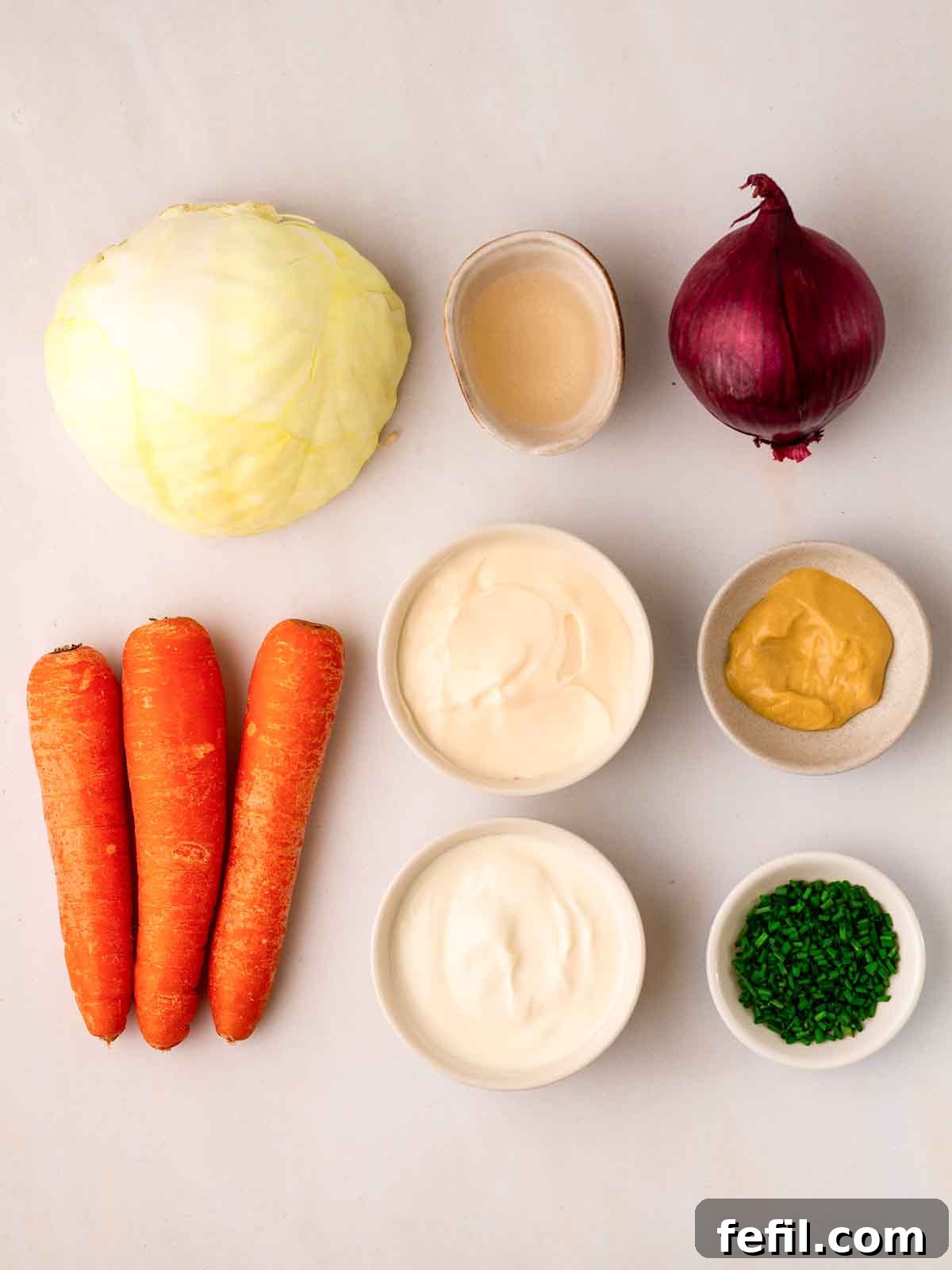 All the fresh ingredients for making homemade coleslaw laid out neatly on a kitchen counter.