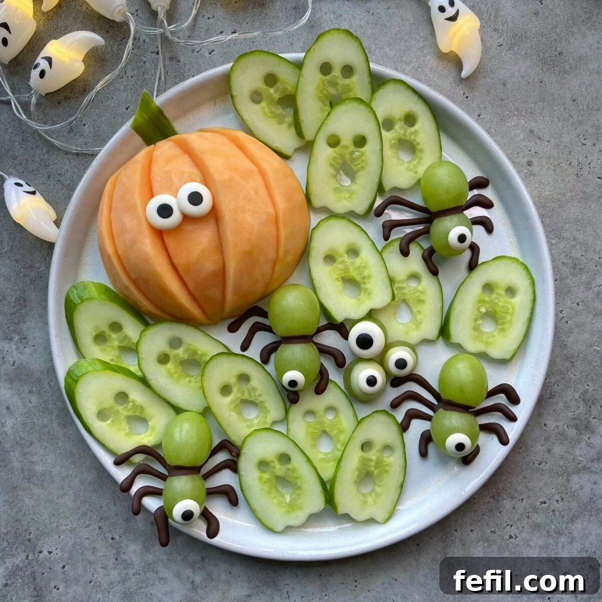 Frightfully Fruity Platter 2 A vibrant Halloween fruit tray featuring a cantaloupe pumpkin with candy eyes, eerie cucumber ghosts, and whimsical grape spiders with pretzel legs, arranged on a festive platter. Perfect for healthy, spooky snacking.
