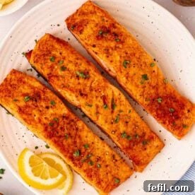Perfectly cooked air fryer salmon fillets with fresh lemon wedges, presented on a white plate, ready for a healthy meal.