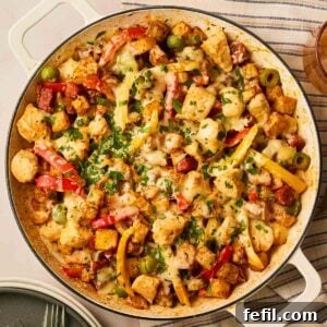 A pan filled with a delicious Air Fryer Chicken, Chorizo, and Potato Tray Bake, topped with melted cheese and fresh parsley, ready to serve as a comforting meal.