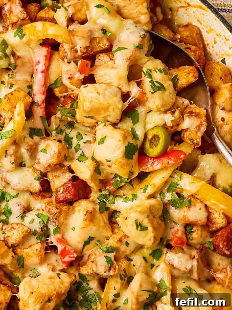 A close-up of a rustic pan brimming with succulent chicken, rich chorizo, vibrant olives, colorful peppers, and perfectly cooked potatoes, all glistening with flavor.