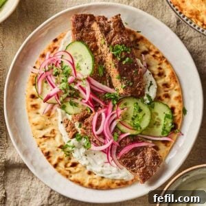 A close up of a sheet pan kebab, made up with salad and sauce and a flatbread underneath.