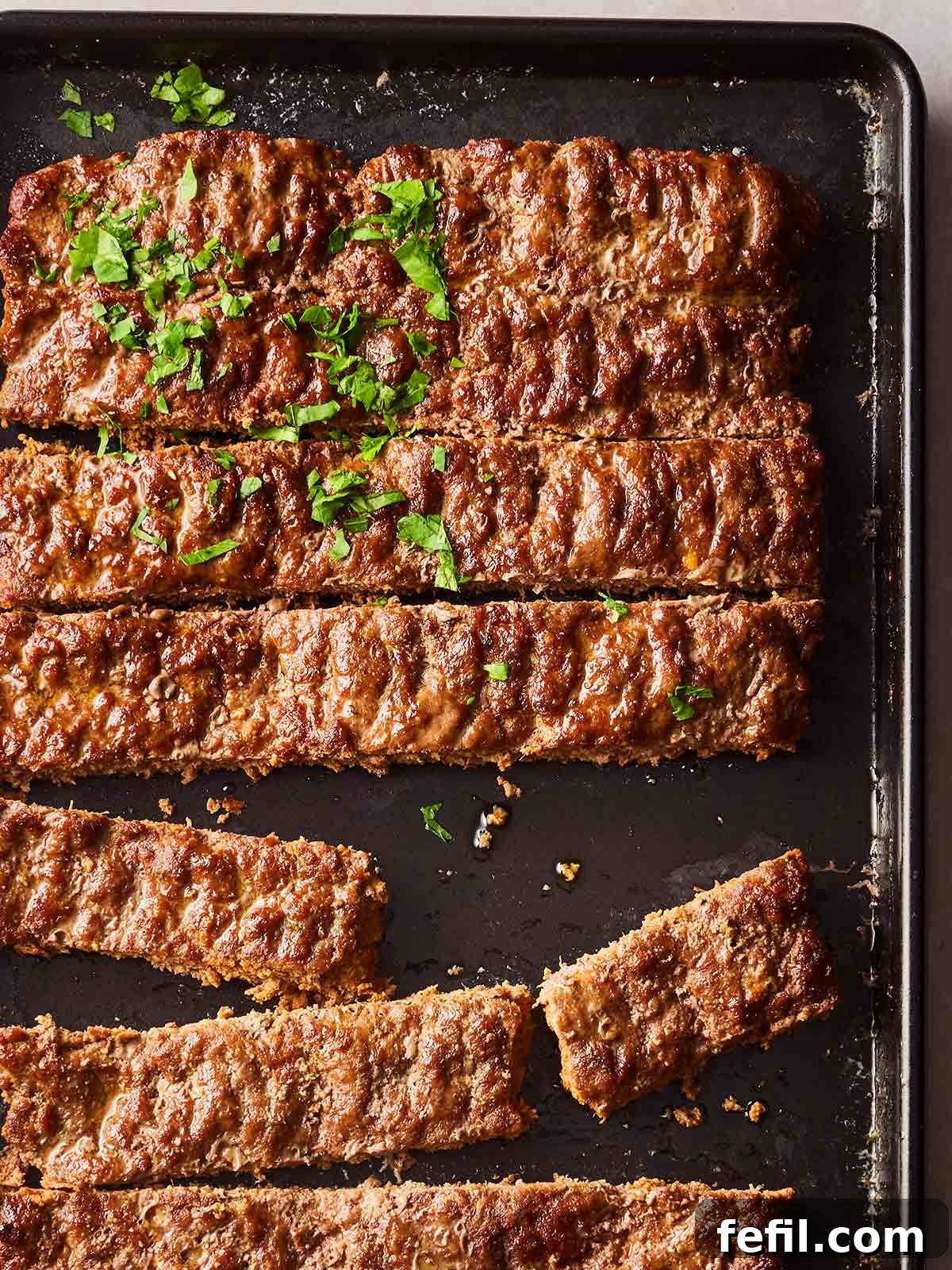 An oven tray with a cooked sheet pan kebab, beef mince in rows, ready to serve.