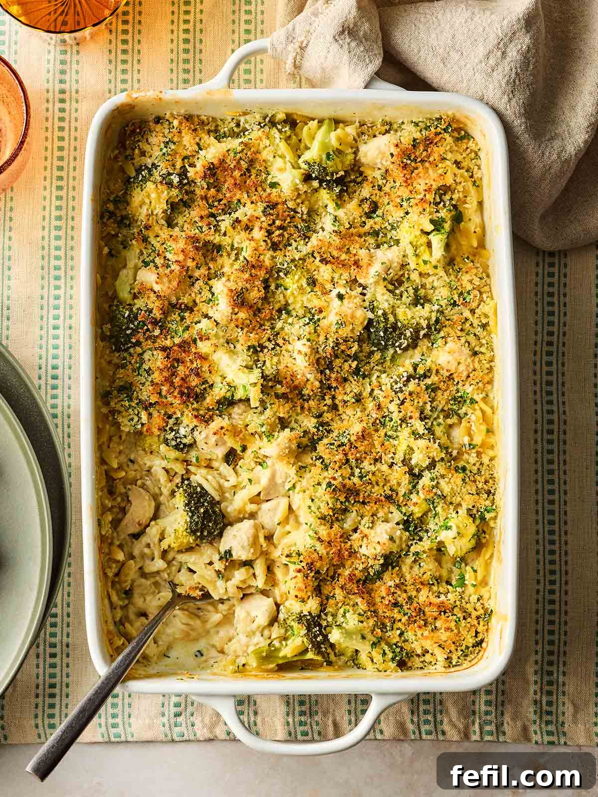 Herb Butter Chicken Pasta 2 A rustic oven dish filled with steaming Chicken Kiev Pasta, featuring golden-brown chicken pieces, vibrant green broccoli florets, and creamy orzo, ready to be served on a wooden table, emphasizing a delicious one-pan meal.