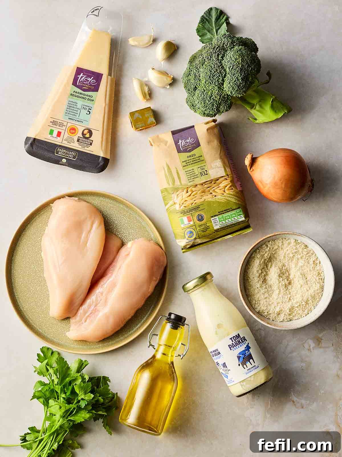 Herb Butter Chicken Pasta 4 A vibrant flat lay of all the fresh ingredients needed for Chicken Kiev Pasta, including raw chicken, garlic, onion, broccoli, orzo, parsley, and various seasonings, neatly arranged on a white background.