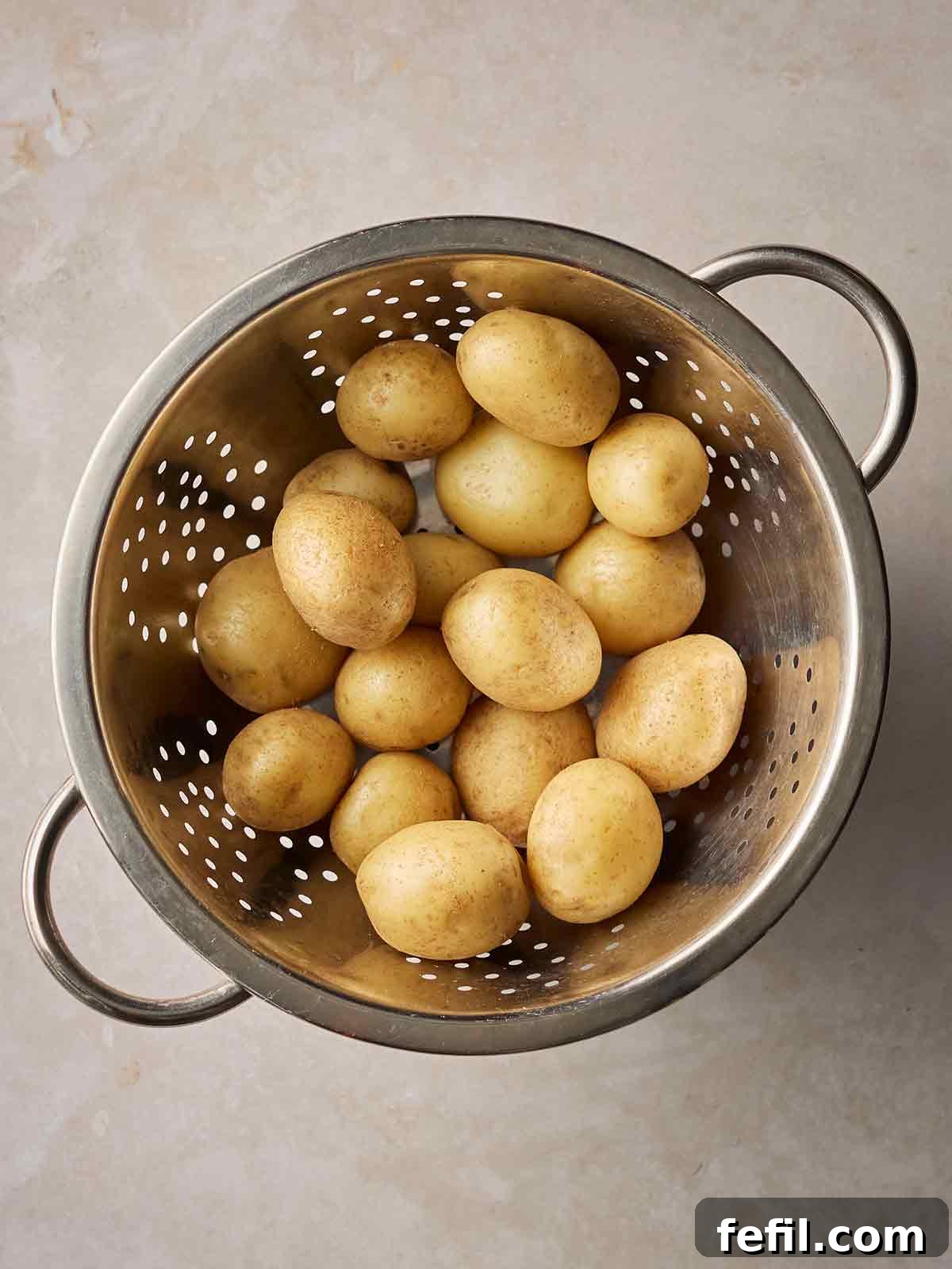 A colander with baby potatoes inside.