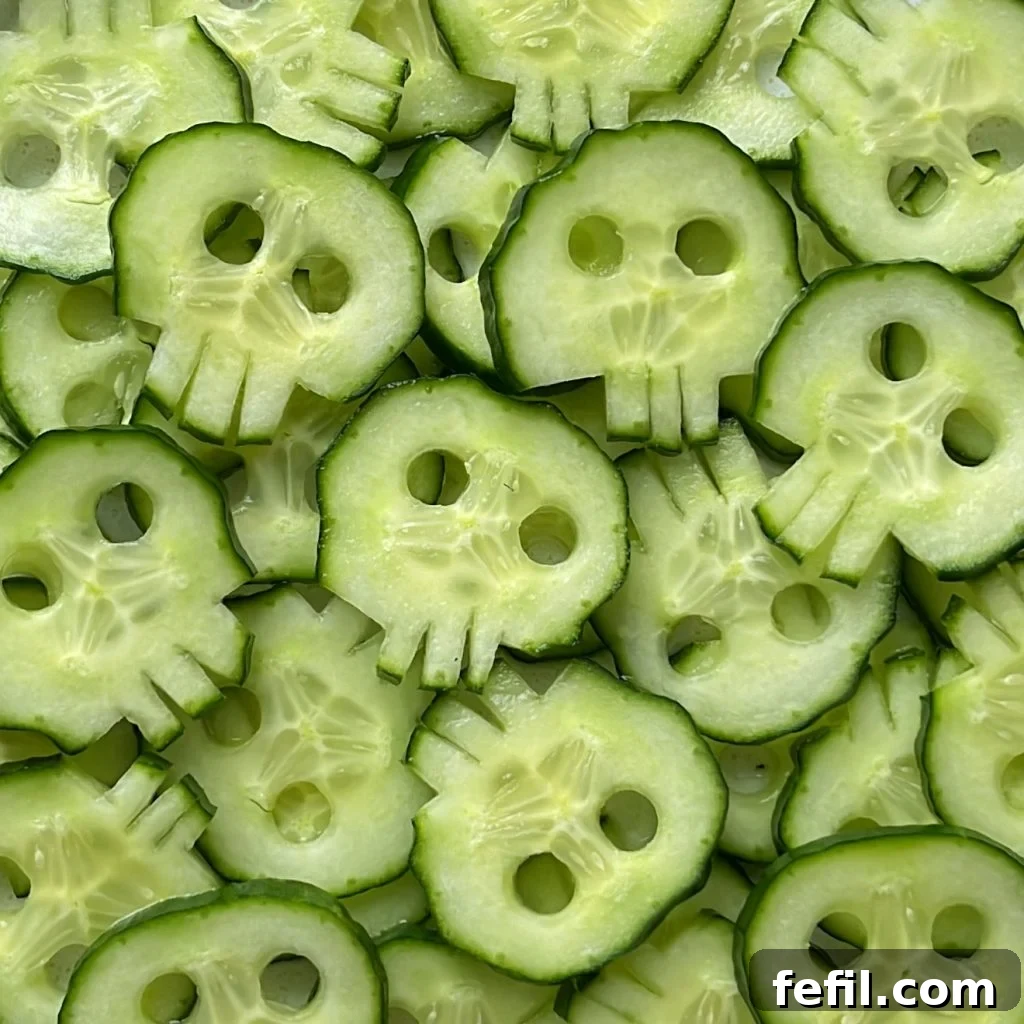 Chilling Cranium Cucumbers 3 Close-up of a carved cucumber skull, showcasing the details of the eyes and mouth, with a metal straw next to it highlighting the simple tools needed for this creative Halloween snack.