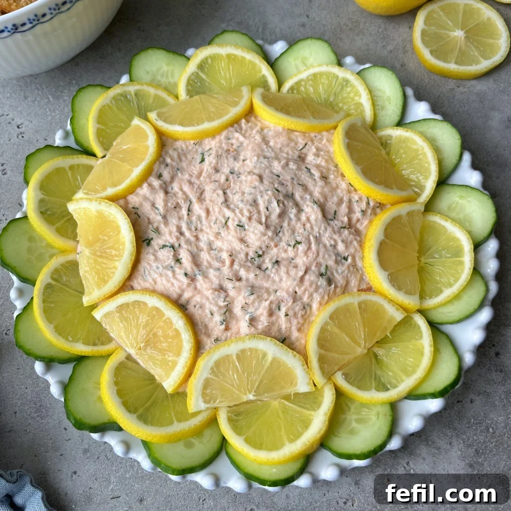 Decadent Hot Smoked Salmon Dip 2 A beautifully plated Hot Smoked Salmon Dip garnished with fresh dill, lemon wedges, and served with various crackers on a rustic wooden board.