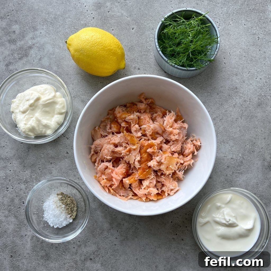 Decadent Hot Smoked Salmon Dip 3 Close-up of the Hot Smoked Salmon Dip ingredients laid out on a table: smoked salmon, Greek yogurt, crème fraîche, lemon, fresh dill, and cucumber.
