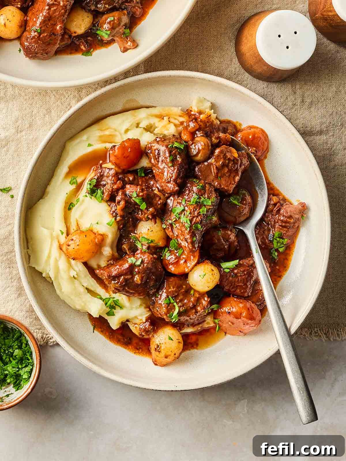 A close-up of a serving of beef bourguignon with mashed potato, garnished with fresh parsley, ready to be enjoyed.