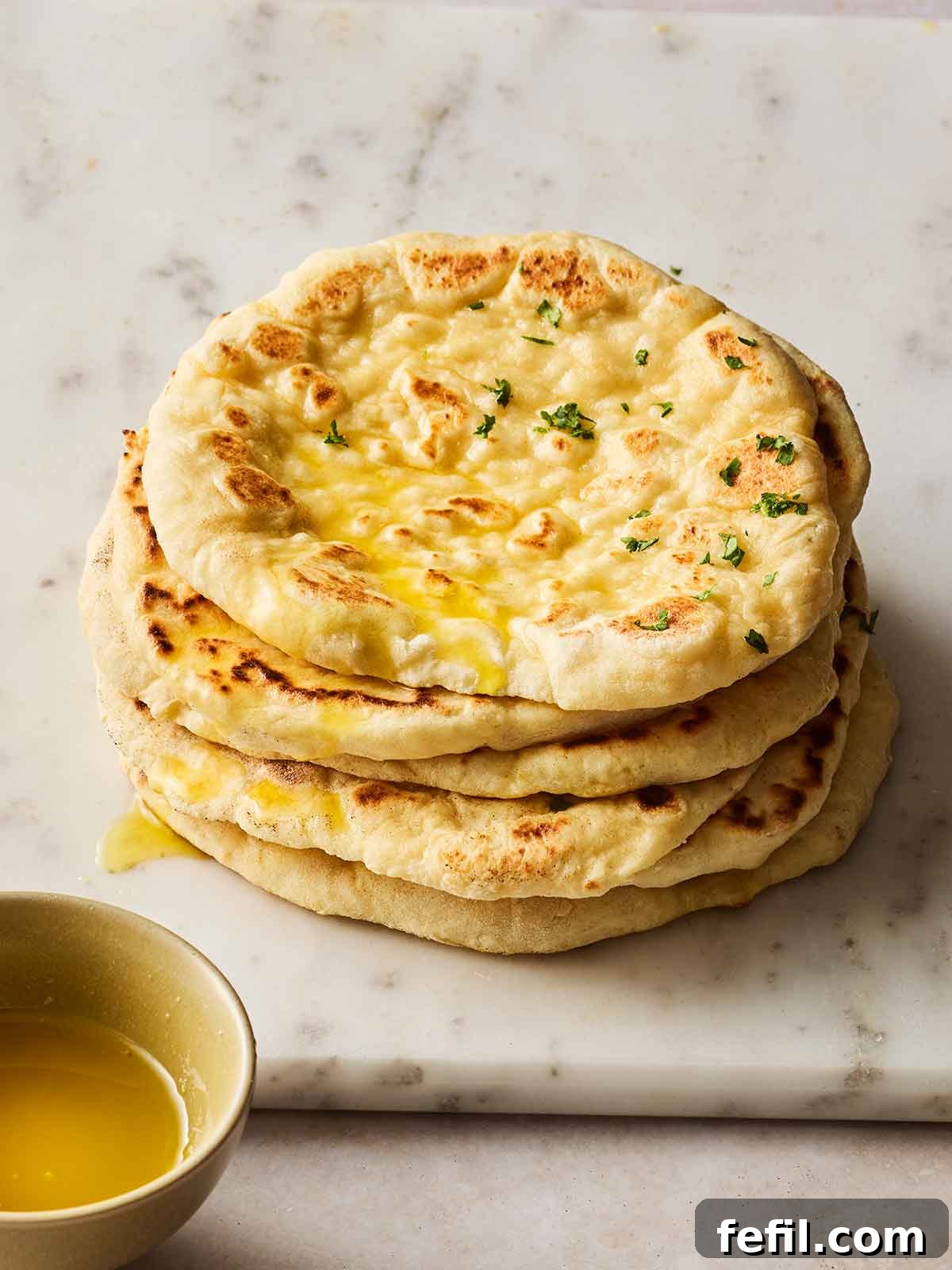 A pile of round homemade flatbreads on a white surface, ready to be served.