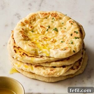 A pile of soft, homemade flatbreads resting on a white marble surface.