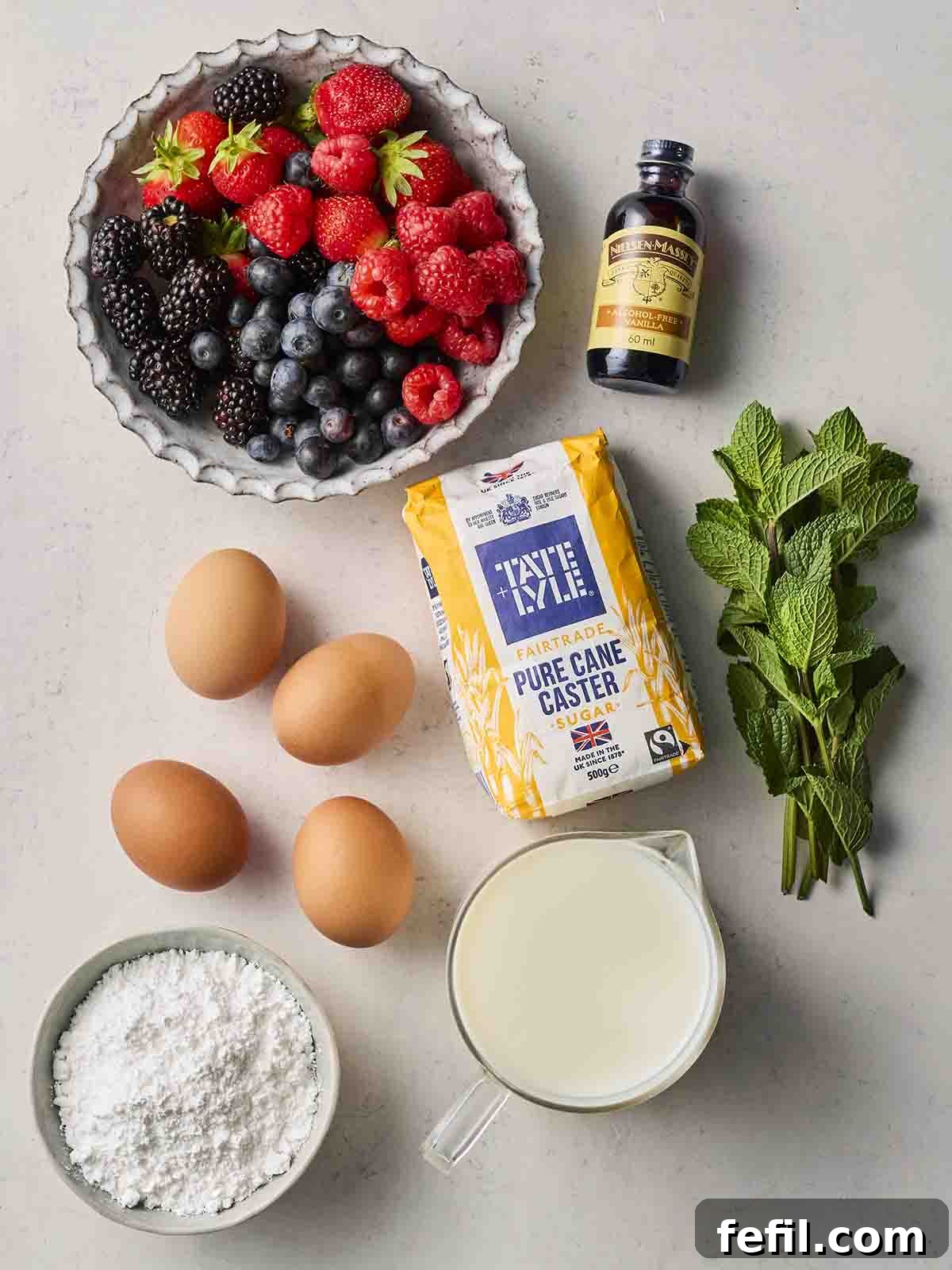 Perfect Pavlova, Made Simple 4 A selection of fresh ingredients laid out on a kitchen counter, including eggs, caster sugar, double cream, vanilla extract, a variety of fresh berries, and mint sprigs.