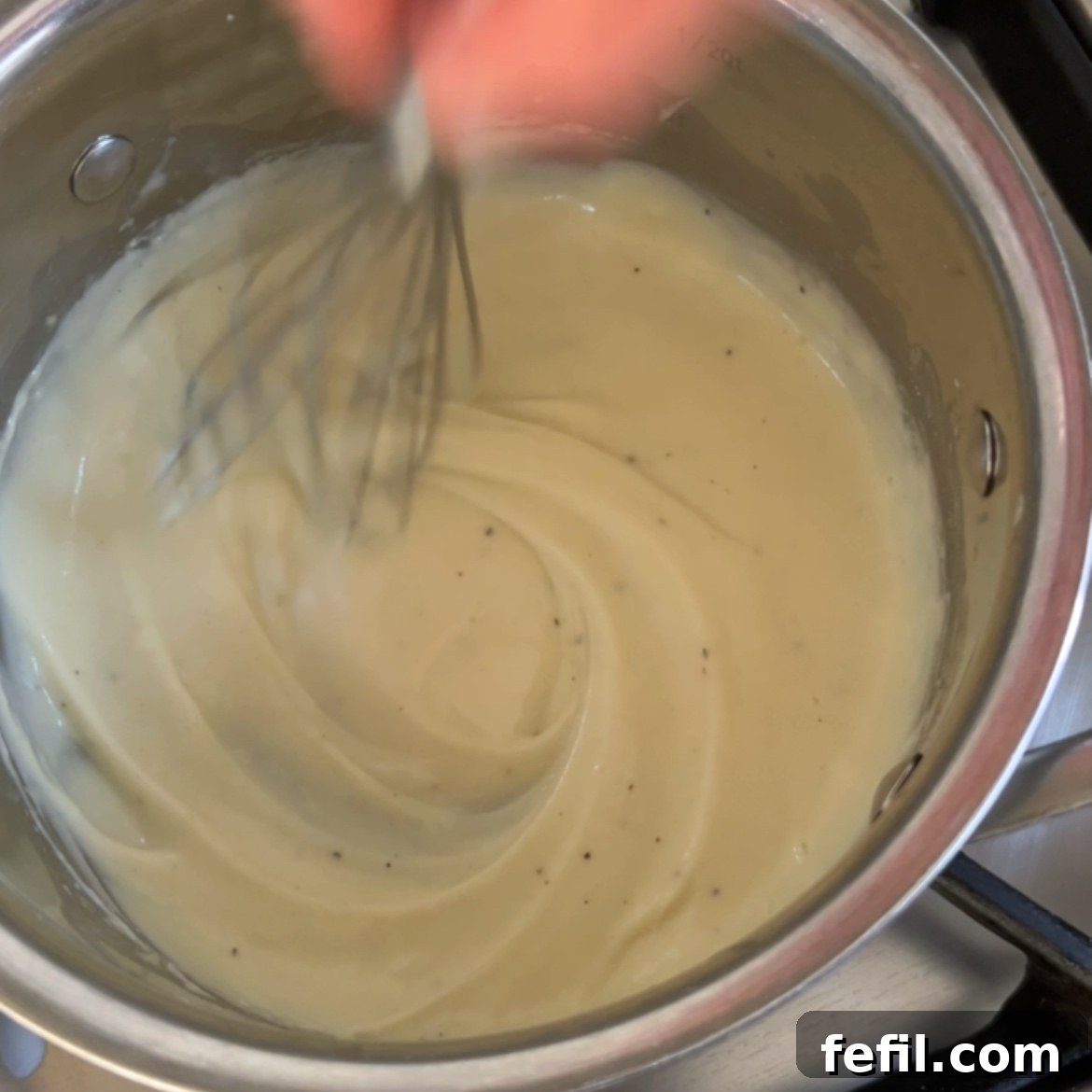 Golden Baked Ham and Cheese Sandwich 6 A person meticulously whisking a creamy béchamel sauce in a shining stainless steel saucepan on a stovetop, ensuring a smooth and lump-free consistency for the Croque Monsieur.