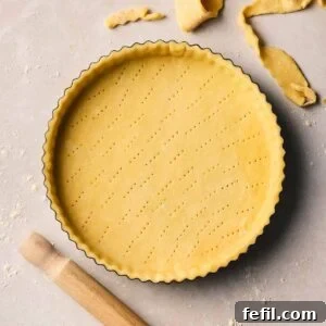 A close up of unbaked shortcrust pastry in a flan dish, ready to bake.
