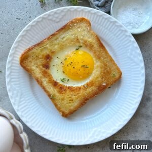 Egg-in-a-Hole Recipe: Crispy Toast with Runny Yolk 13 Toasted white bread filled with an egg in the center and topped with fresh thyme.
