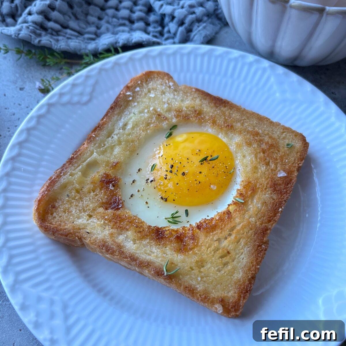 Egg-in-a-Hole Recipe: Crispy Toast with Runny Yolk 3 Sideview of a piece of toast with a baked egg in the center.