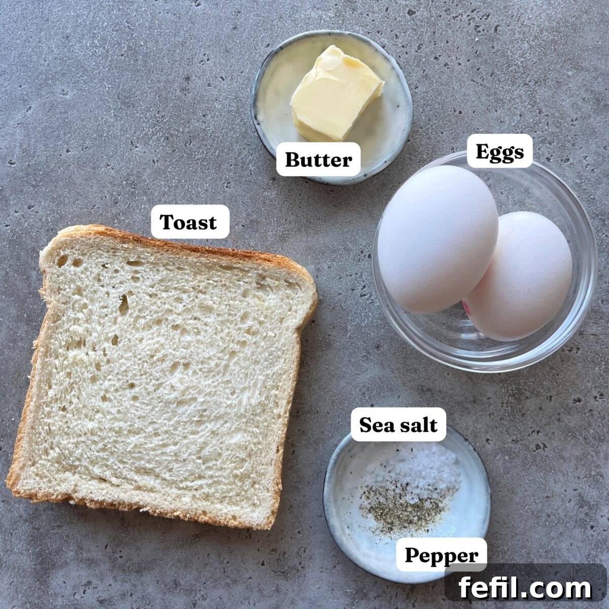 Egg-in-a-Hole Recipe: Crispy Toast with Runny Yolk 4 Ingredients for eggs in a hole, with two pieces of toast, butter, two eggs, and a bowl of sea salt, and pepper.