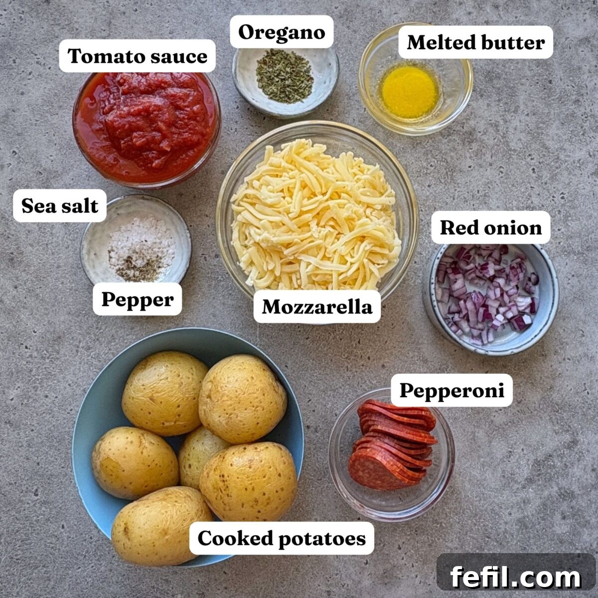 Ingredients for Smashed Potato Pizza featuring bowls of cooked potatoes, tomato sauce, melted butter, mozzarella, diced red onion, pepperoni, oregano, and sea salt and pepper.