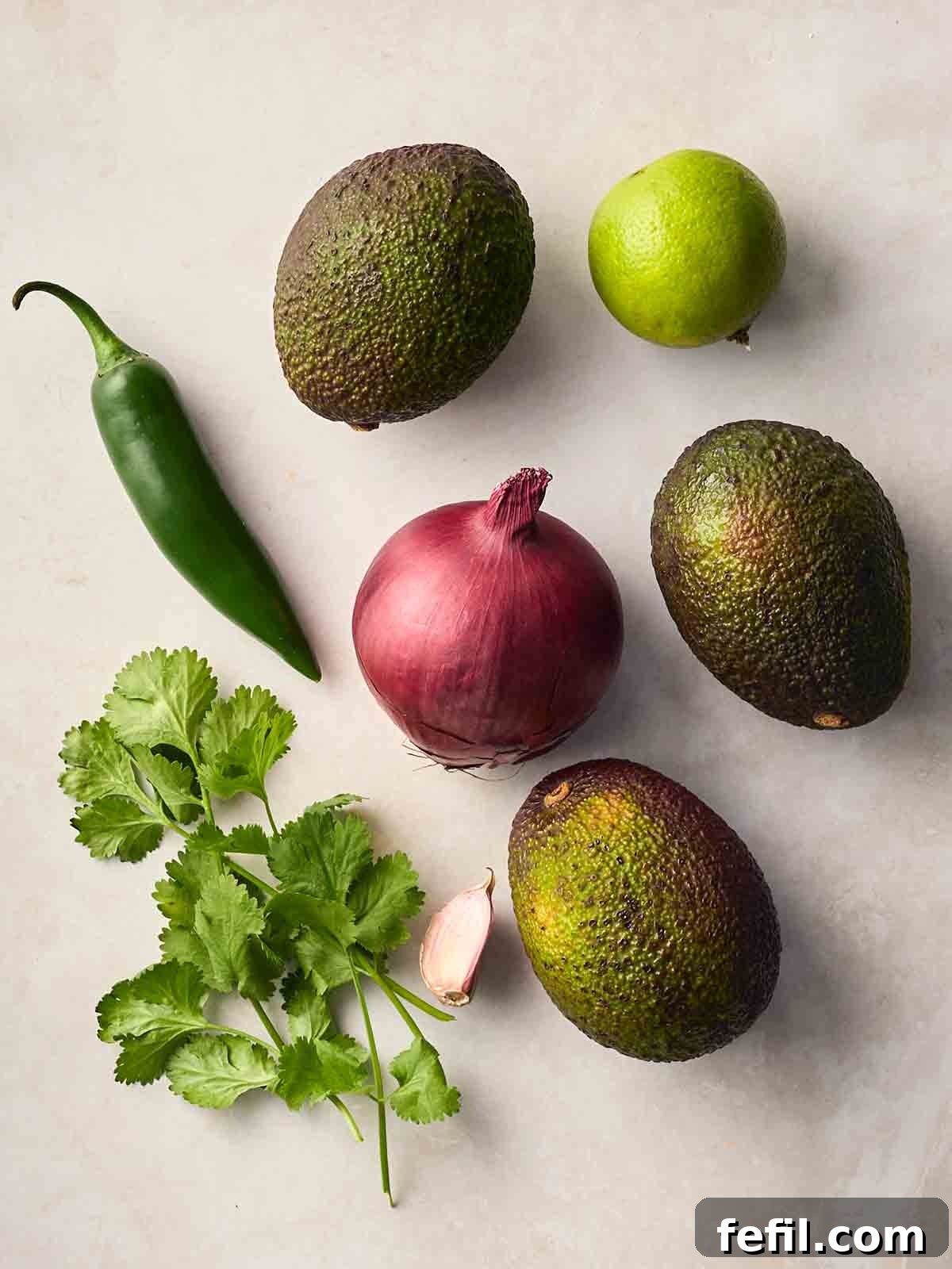 Fresh Guacamole Recipe: Zesty Homemade Mexican Dip 4 The ingredients for making homemade guacamole laid out on a white surface.